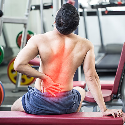 Man sitting on exercise bench holding back in pain